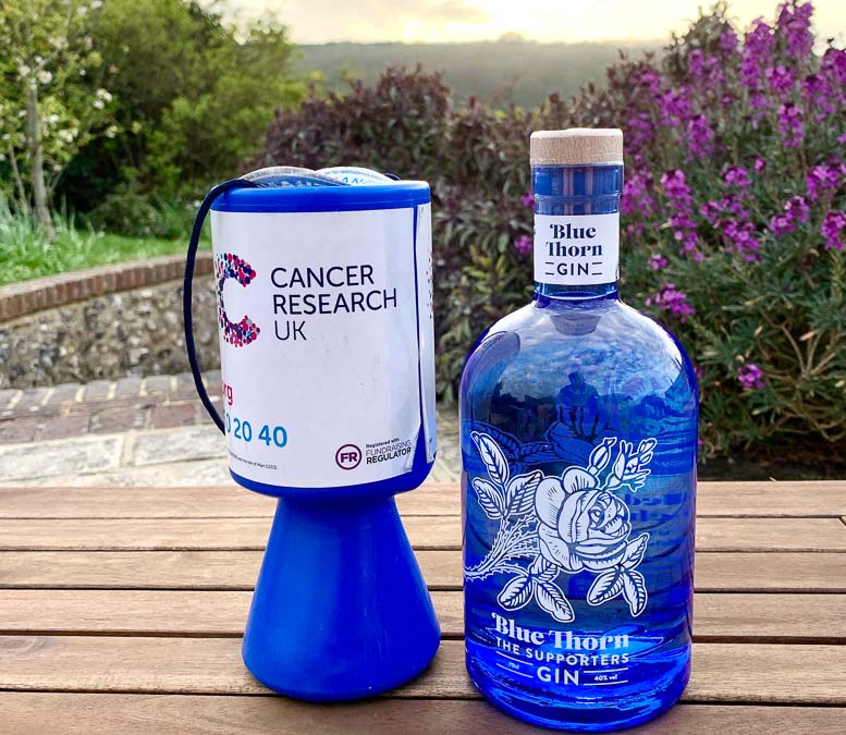 Bottle of Blue Thorn Gin next to Cancer Research Collecting tin
