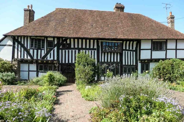 Pilgrim's Rest, Battle East Sussex an ancient long hall with black timbers and white plaster with tiled roof. Herbs and lavender are in the garden at the front