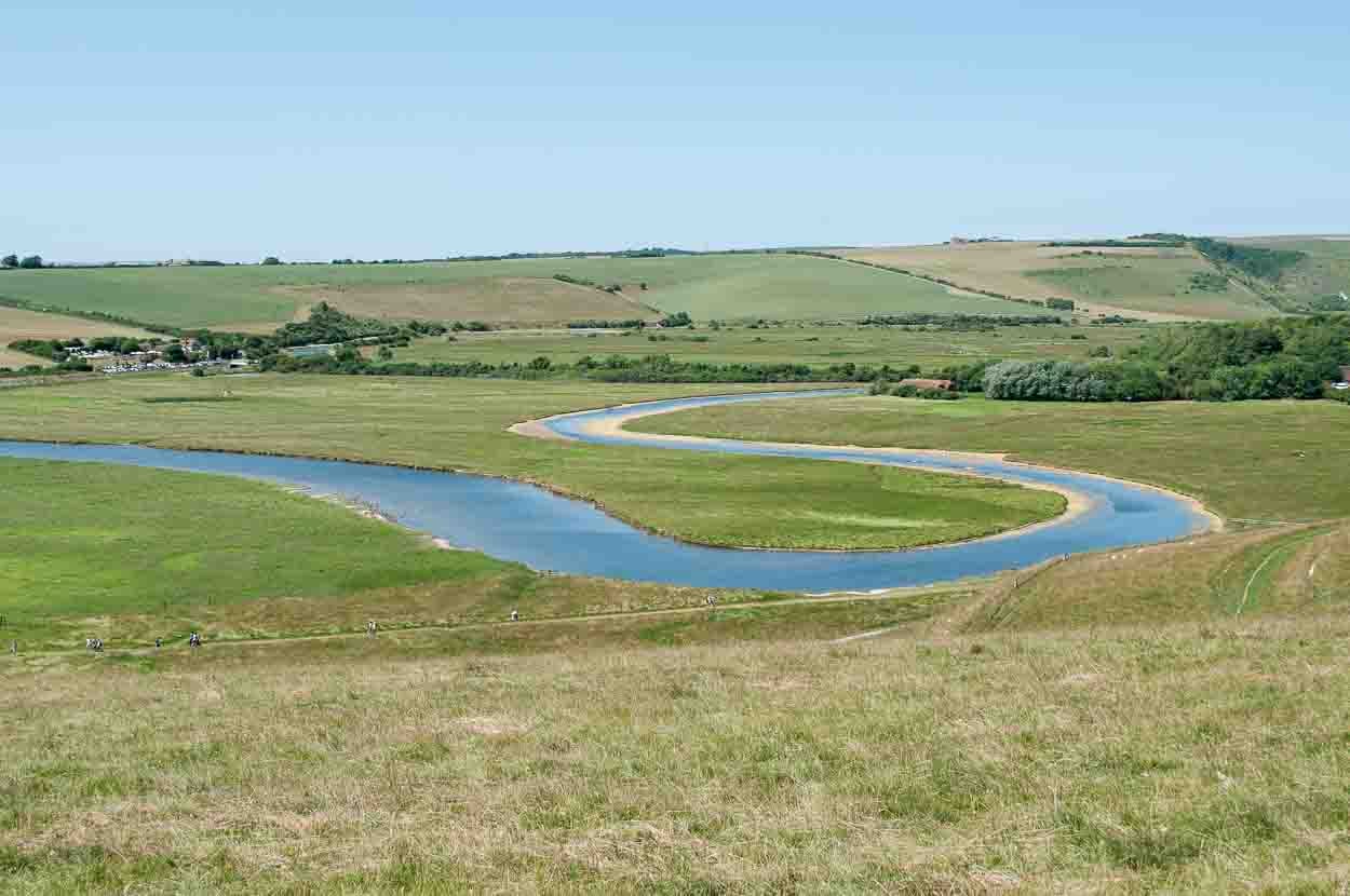 The blue river Cuckmere winding through green fields and forming the shape of an S