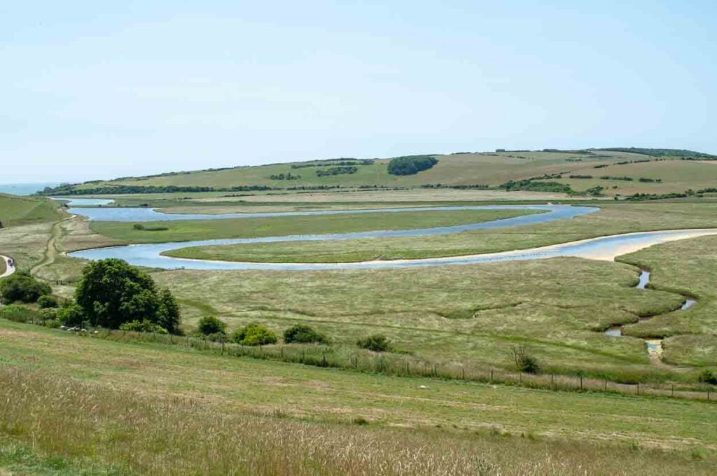 The blue river Cuckmere winding through green fields and countryside and forming the shape of an S