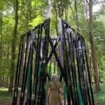A woman walks through Eva Rothschild's Cosmic in a woodland setting